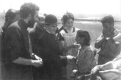 Grup de cinc persones en un camp, amb una dona lliurant un objecte a una altra dona.