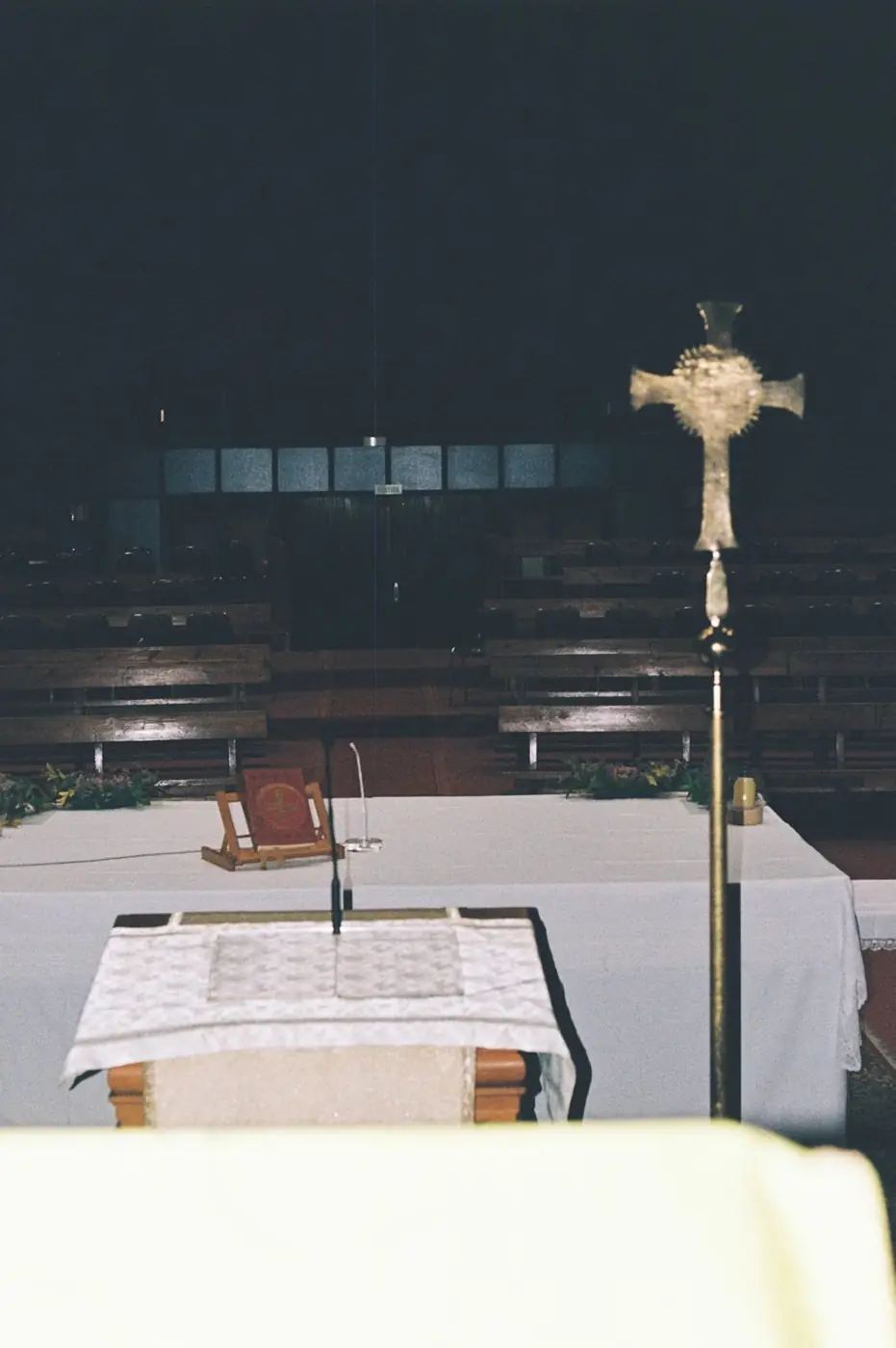 Altar del templo con mantel blanco, atril y cruz procesional